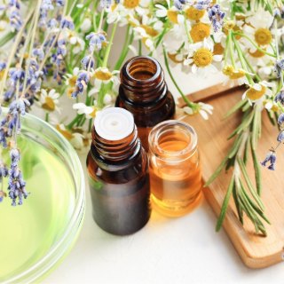 Frascos de óleo essencial ao lado de lavanda e camomila frescas