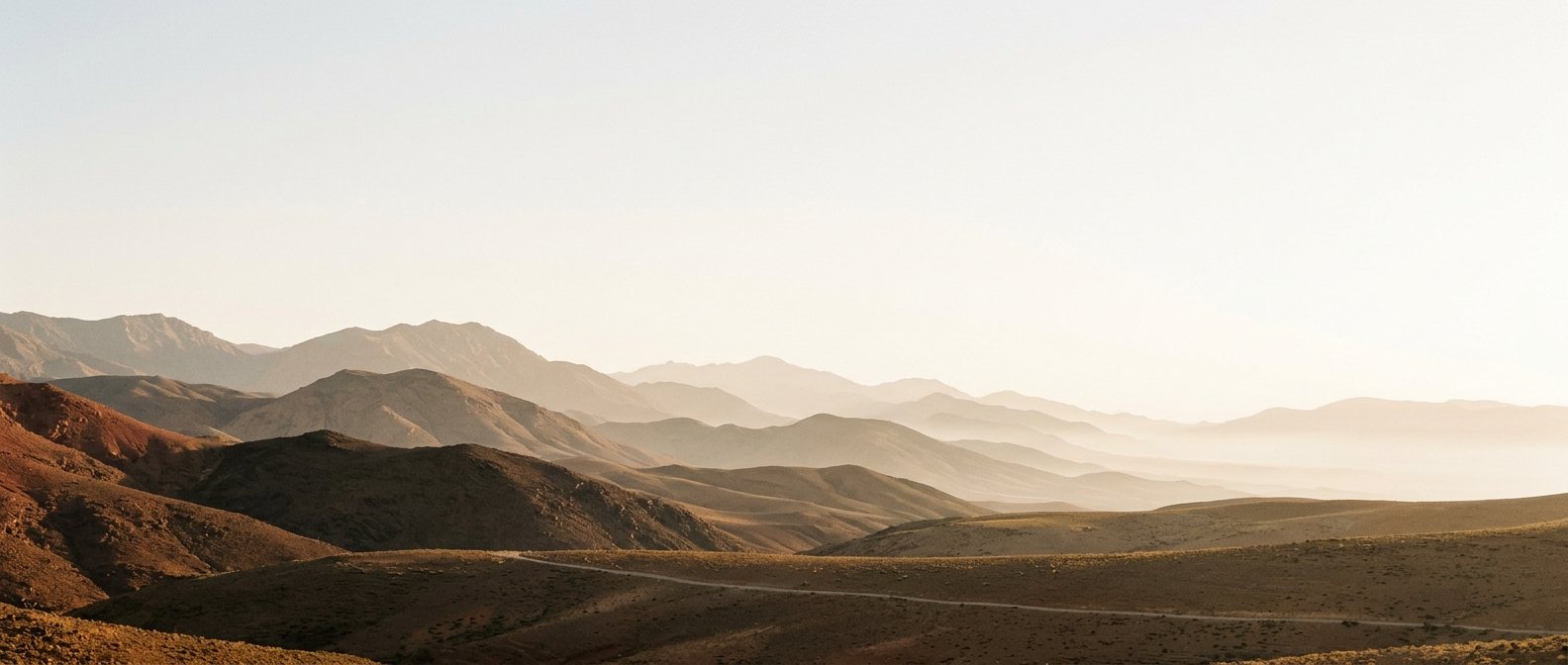 Panorâmica das montanhas do Atlas ao amanhecer, com camadas de serras se afastando na bruma